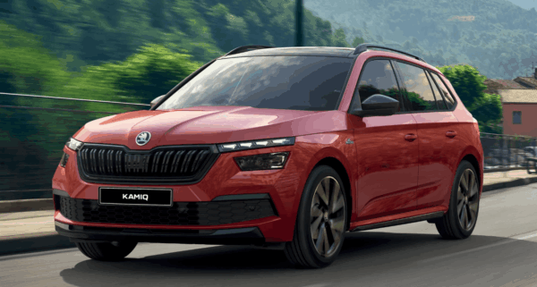 Red Škoda Kamiq driving through a scenic urban setting, highlighting its compact SUV style and bold front grille