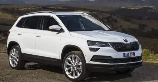 White Škoda Karoq parked in an open rural landscape, showcasing its mid-size SUV build and high ground clearance